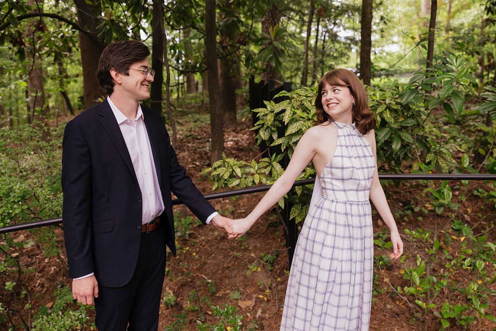 Elizabeth and Nicholas holding hands in a wooded garden.