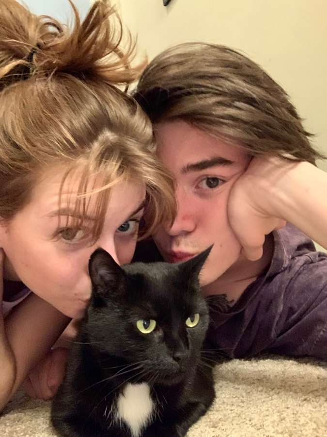 Elizabeth and Nicholas lying on the floor with their black cat, Gloria.